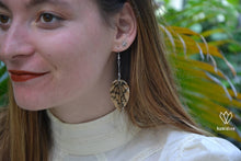 Charger l&#39;image dans la galerie, Jeune femme portant des boucles d&#39;oreilles argentées en origami noires et marrons en forme de feuille
