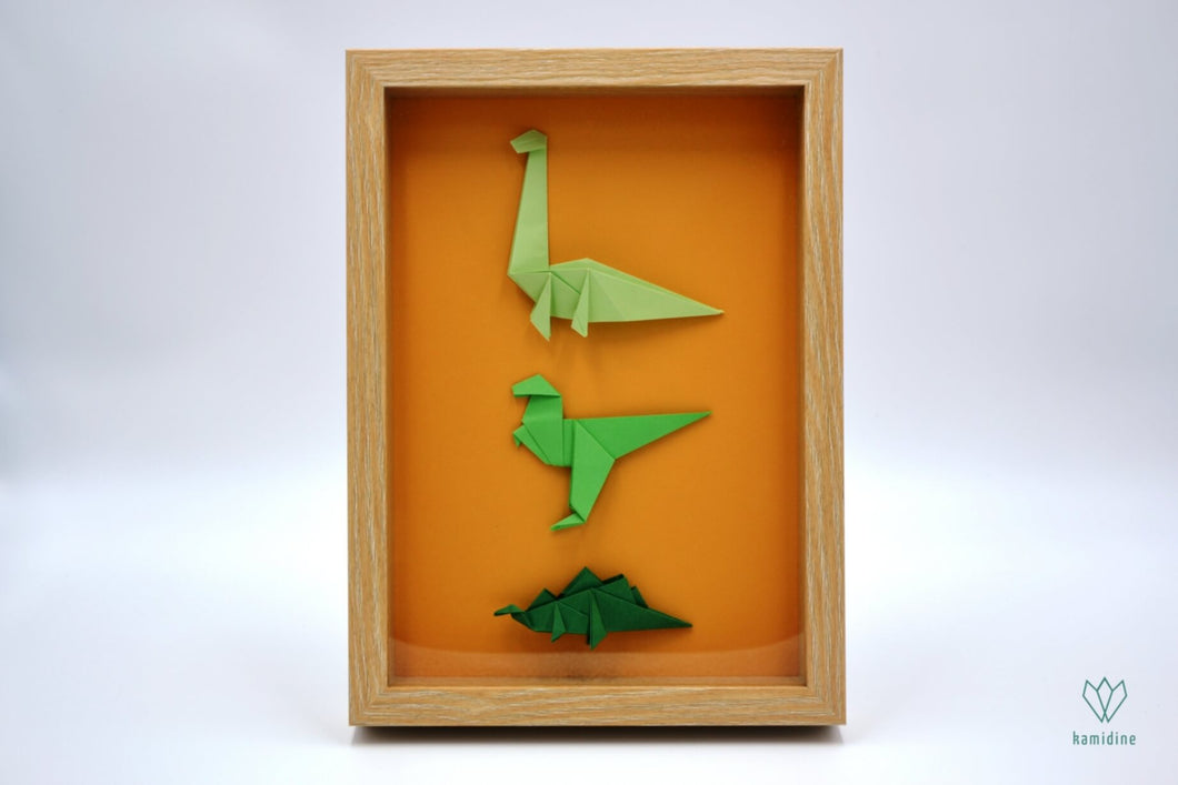 Cadre avec des dinosaures en papier origami verts sur un fond orange