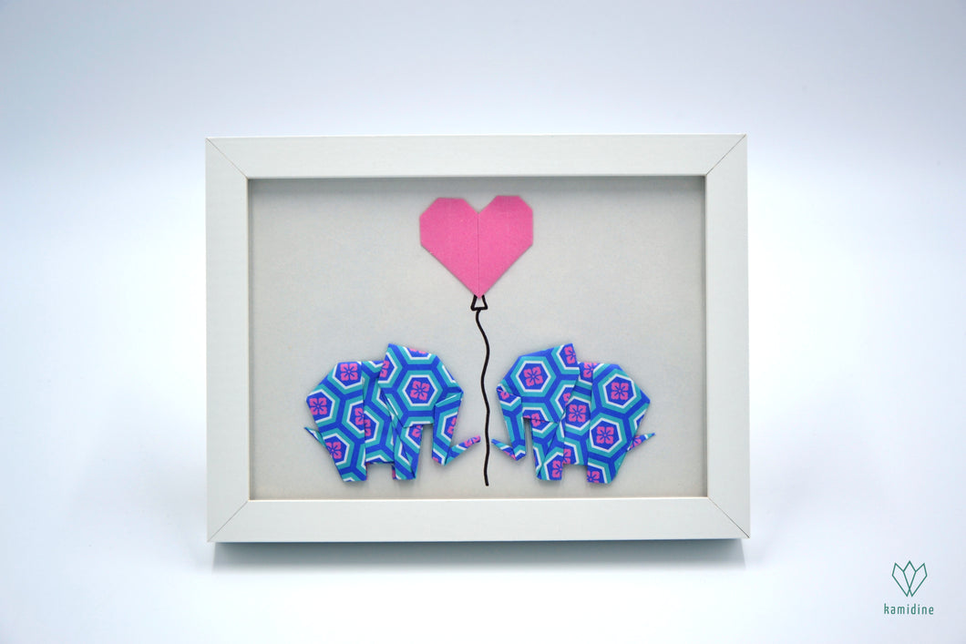 Duo d'éléphants bleu et rose et cœur rose en papier origami dans un cadre blanc